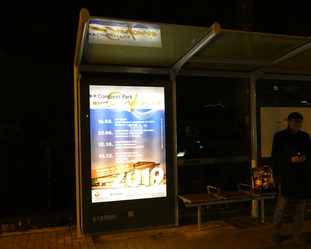 Bushaltestelle im Dunklen mit Citylight Plakat